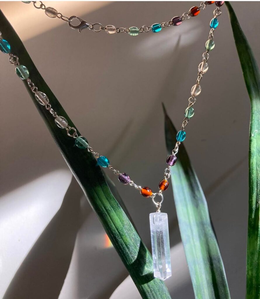 “Close-up of  a handmade crystal pendant necklace with colorful beaded chain, highlighting the unique craftsmanship and personal touch of handmade jewelry.”
